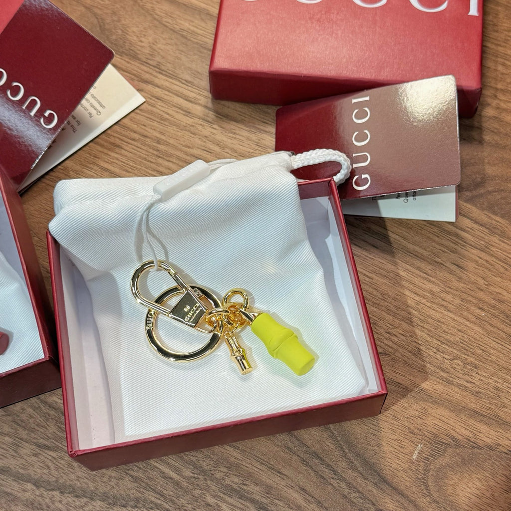 Gucci keychain accessory in open red box: gold ring, lock charm, lime green tag