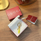 Gucci keychain on white drawstring pouch, with lime green charm and gold ring