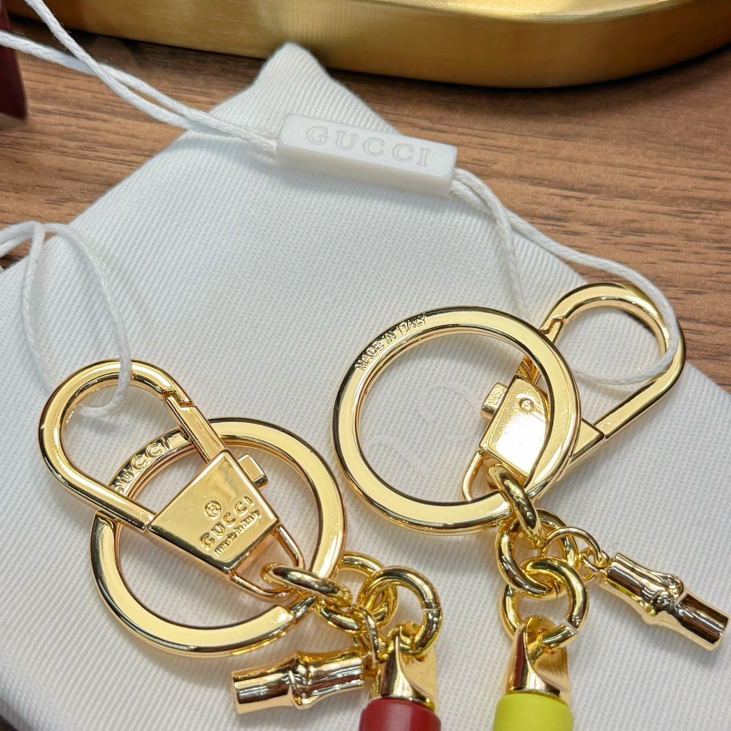 Gold-tone circular key rings with lock clasps and lime and red capsule charms