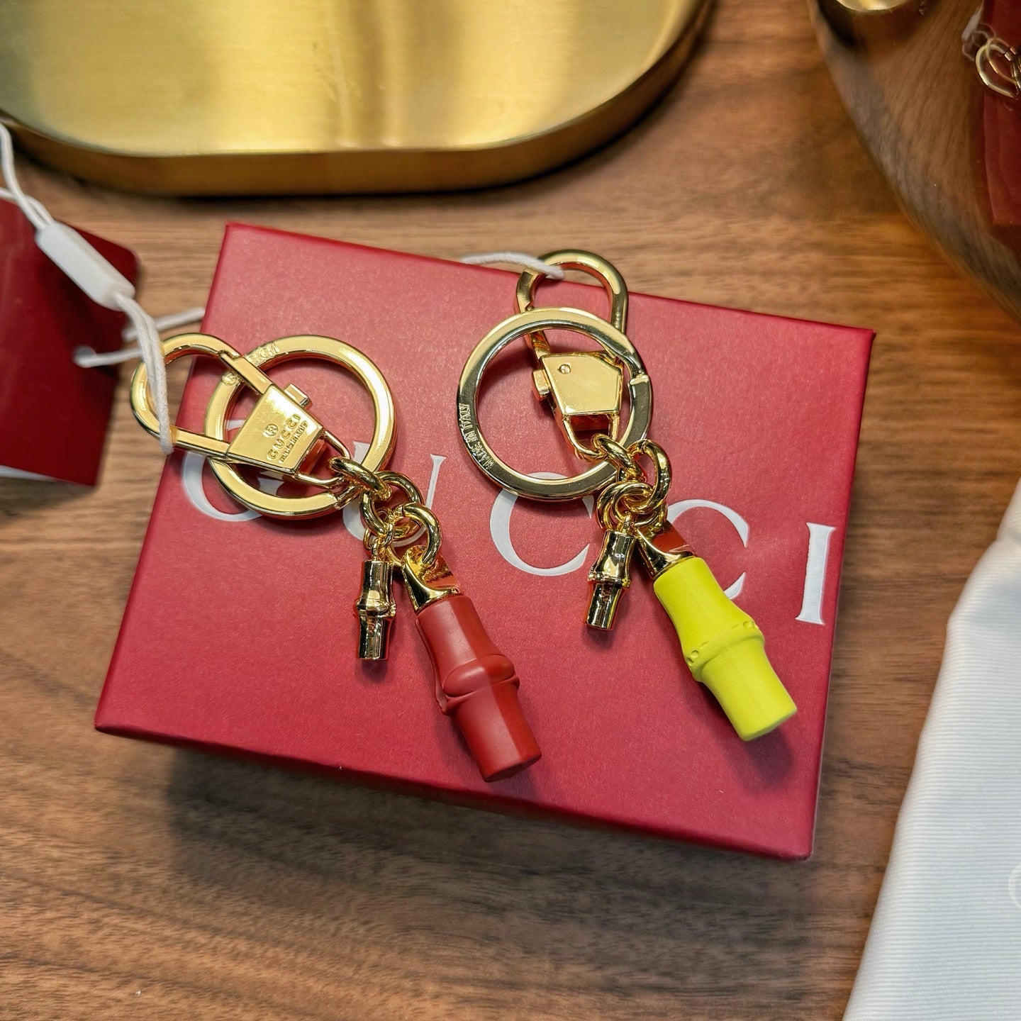 Gold-tone keychain pair with lime and red capsule charms and circular key rings