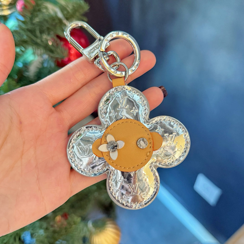Metallic monogram flower keychain with tan leather center and silver clasp loop