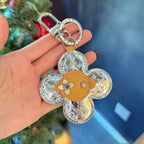 Metallic monogram flower keychain with tan leather center and silver clasp loop
