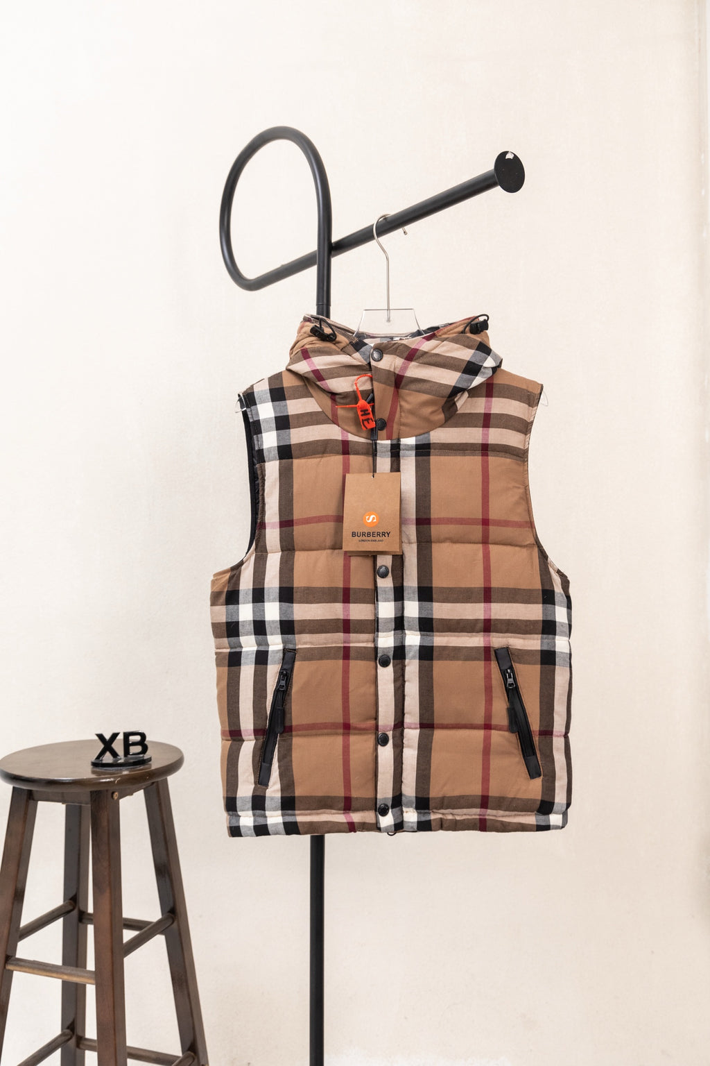 Hooded plaid puffer vest, front view, with brown, black, white, and red check pattern