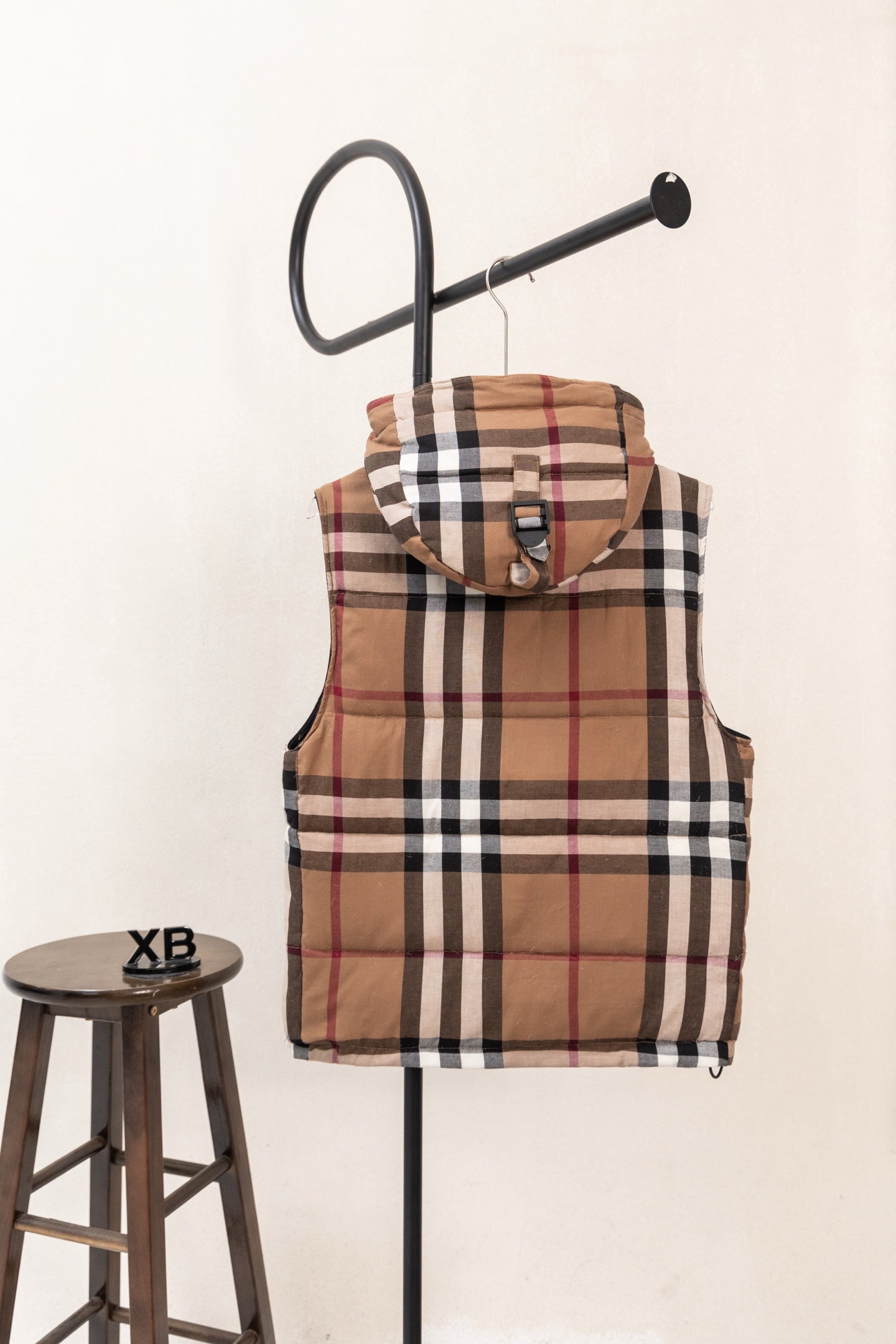 Hooded plaid puffer vest with draped hood and brown, black, white, and red checks