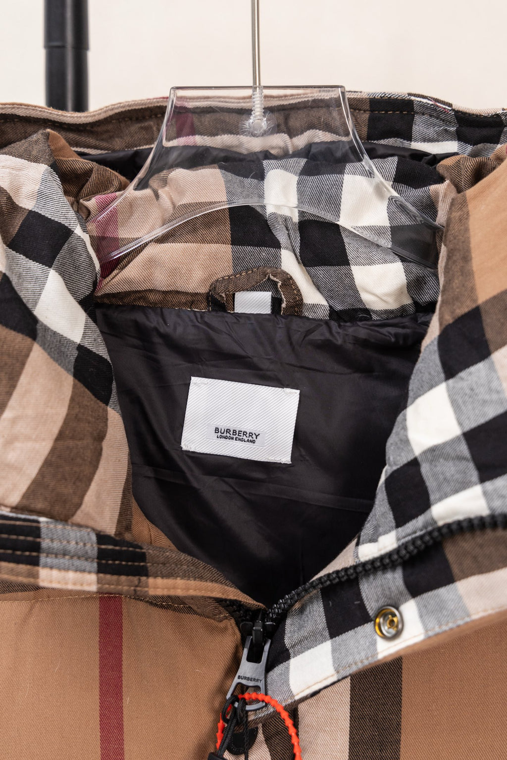Plaid puffer vest inside view with hanging tag and black trim near the neckline