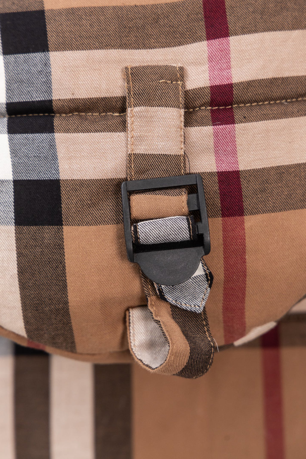 Plaid vest close-up with adjustable buckle strap and fabric patch at the chest