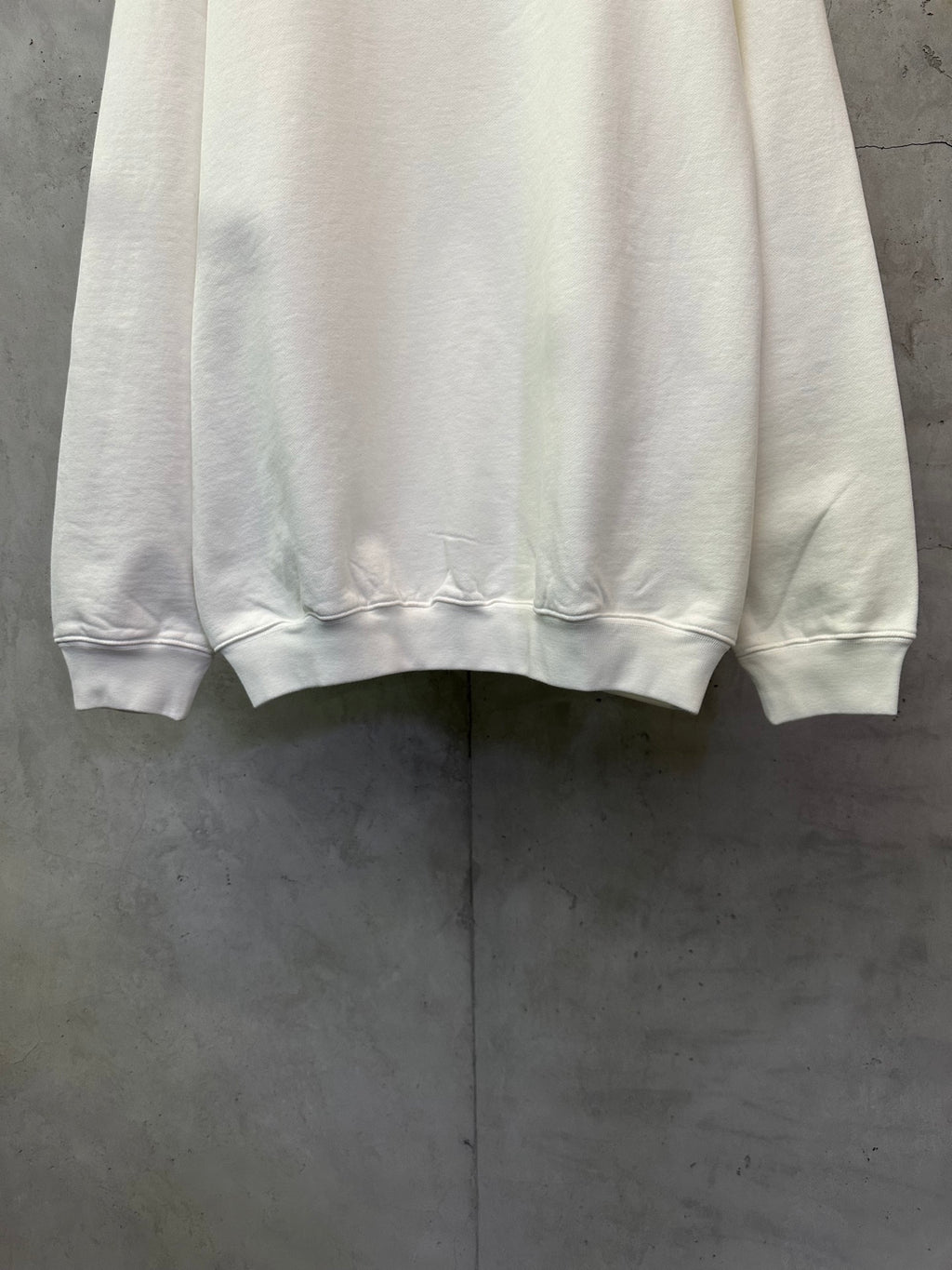 White crewneck sweatshirt hem and cuffs, front folded on display