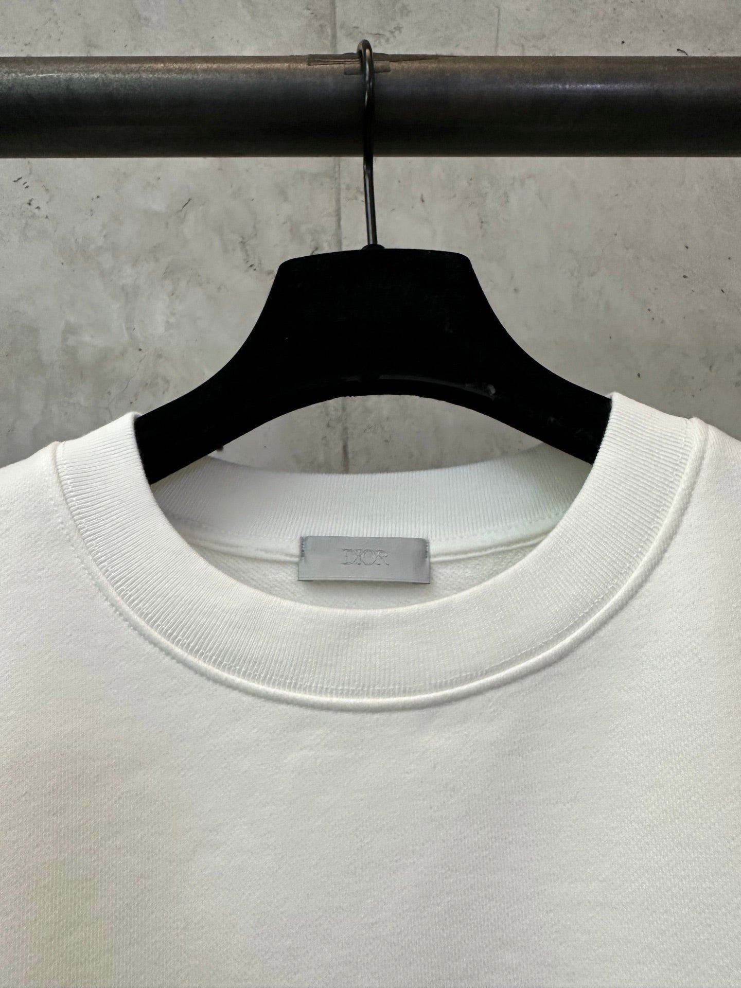 White crewneck sweatshirt collar detail on a hanger
