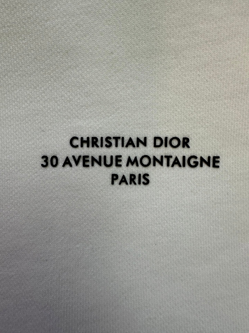 White sweatshirt fabric with "CHRISTIAN DIOR 30 AVENUE MONTAIGNE PARIS" text
