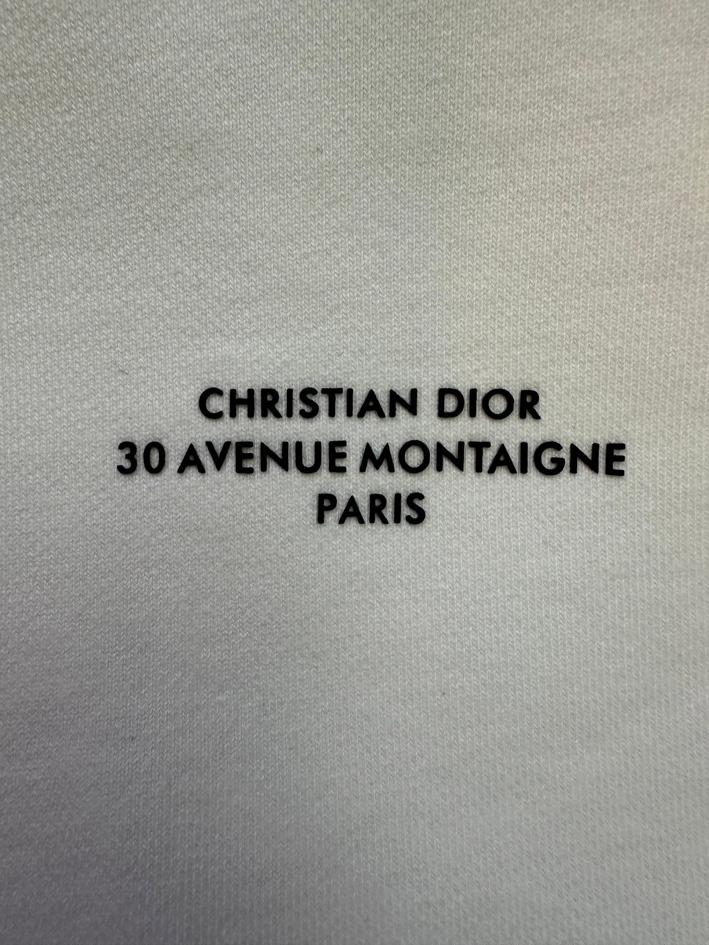 White sweatshirt fabric with "CHRISTIAN DIOR 30 AVENUE MONTAIGNE PARIS" text