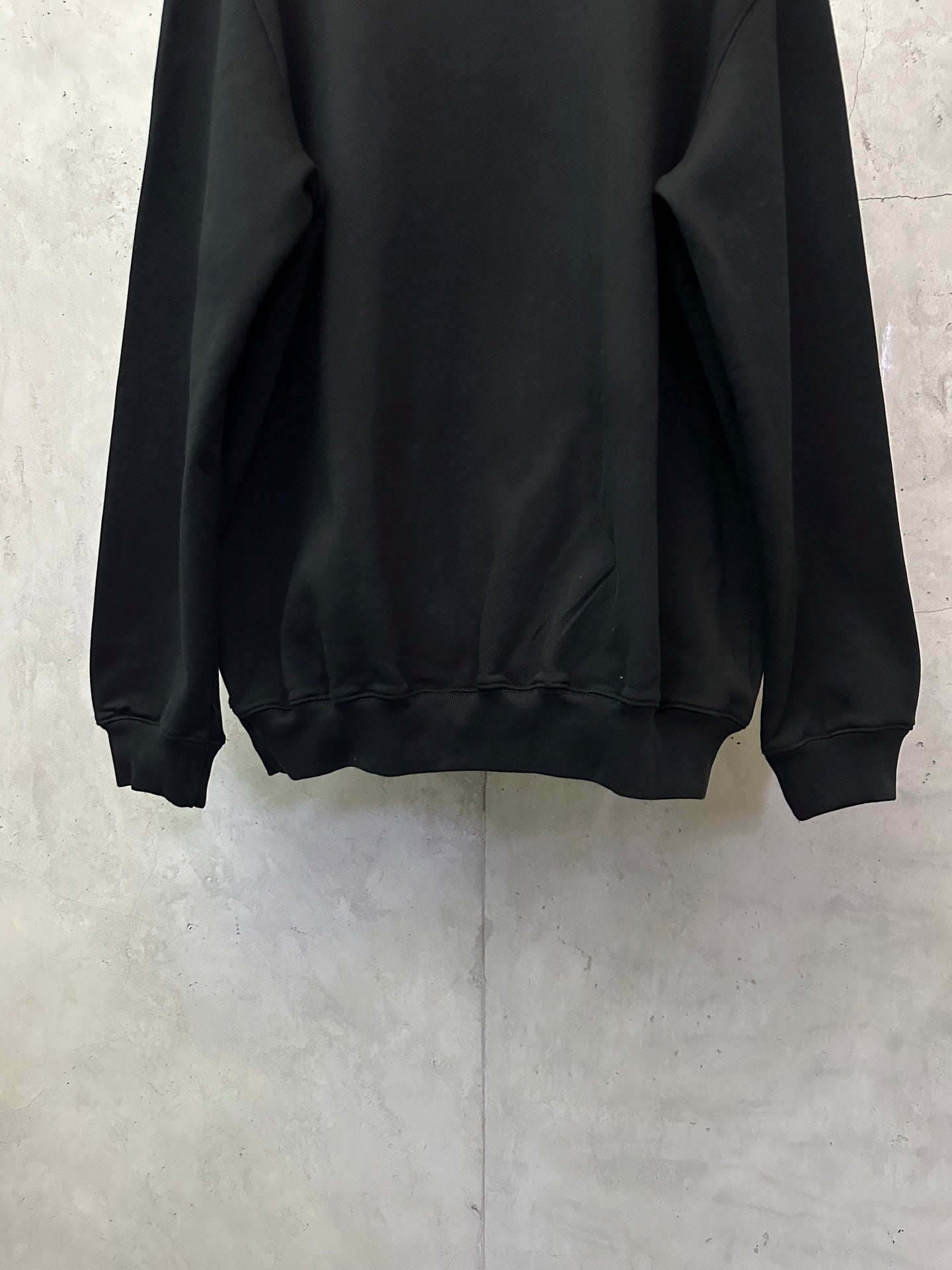 Black crewneck sweatshirt lower back view with ribbed hem