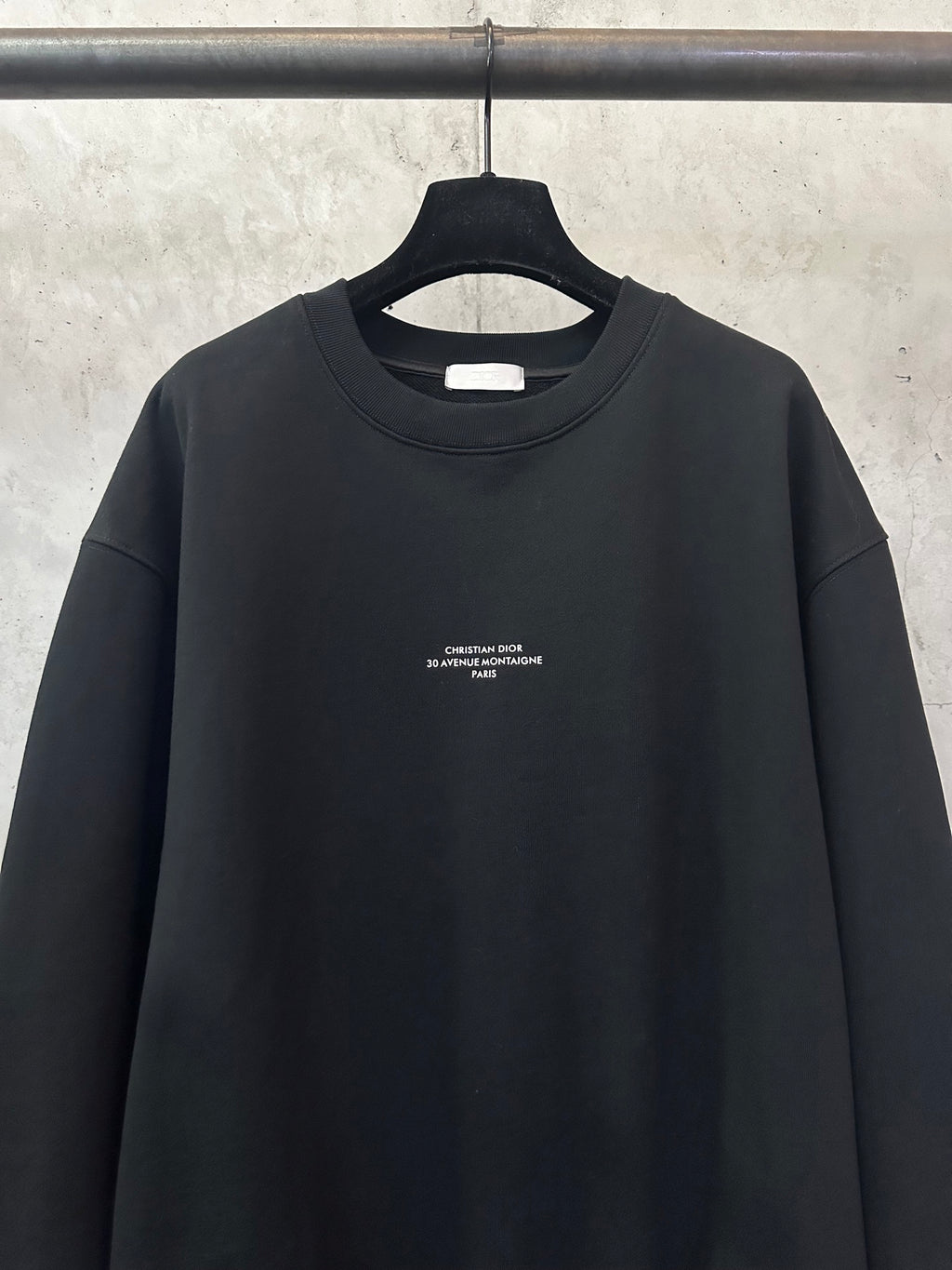 Black crewneck sweatshirt with centered chest text logo