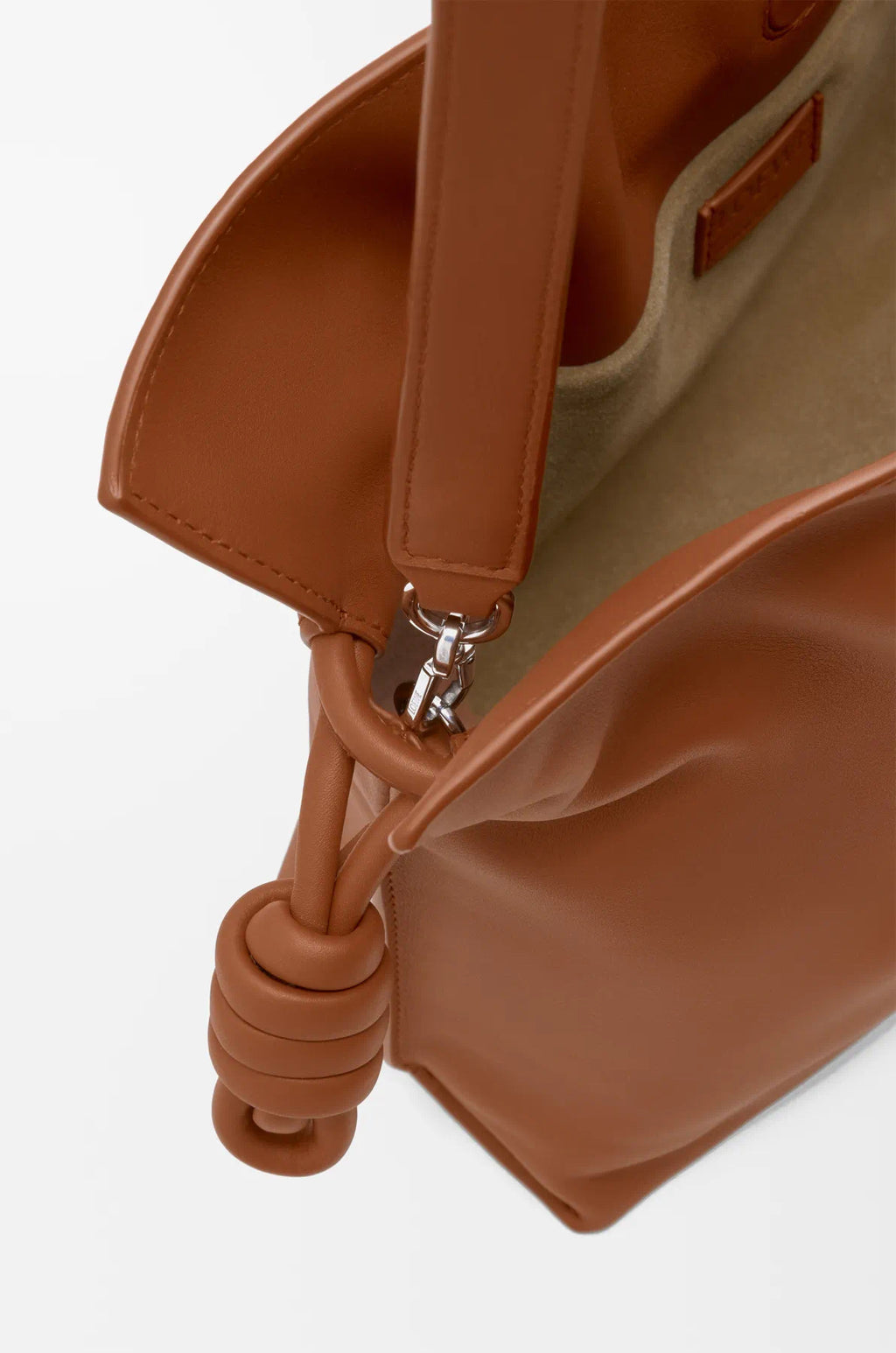 Loewe tan leather bag detail with strap hardware, braided cords, and interior edge