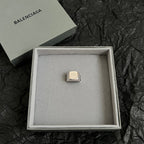 Balenciaga logo accessory with gold-toned rectangular emblem in gift box