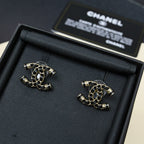 Gold-tone chain stud earrings with black link details on black cushion