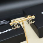 Gold-tone logo hoop earrings with pink stones and faux pearls on display stand