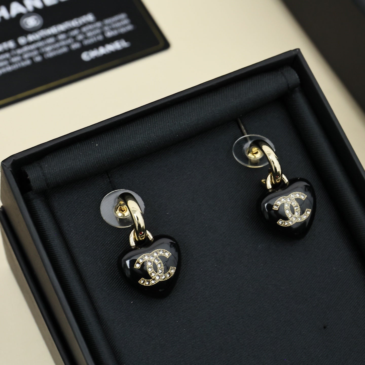 Chanel heart charm earrings, black resin hearts with gold-tone CC emblem and crystal trim.