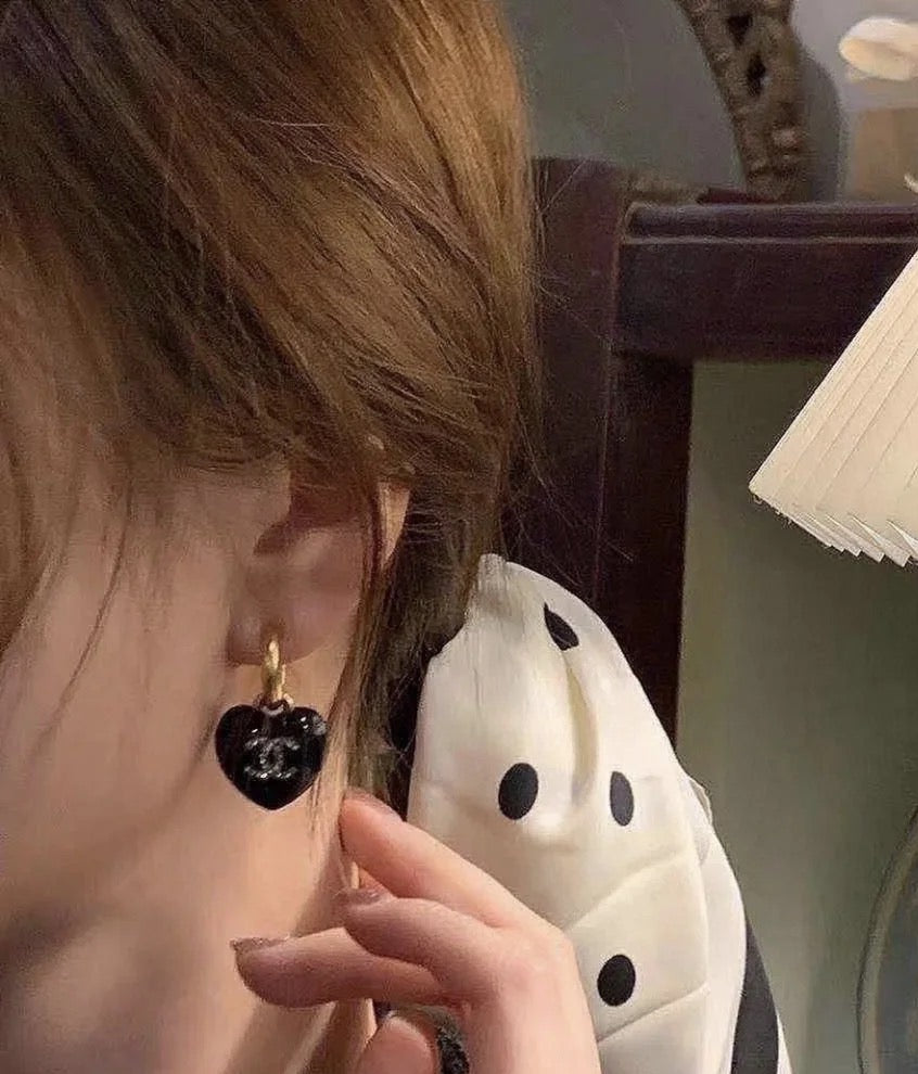 Chanel heart charm earrings, black resin heart charm with gold-tone CC emblem on hooks.