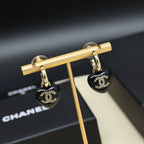 Chanel heart charm earrings on gold display bar, black resin hearts with CC emblem.