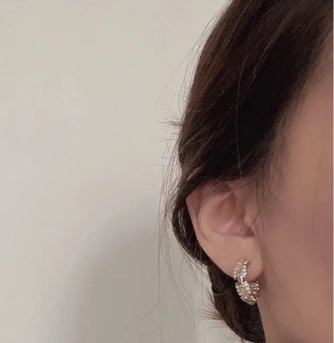 Gold-tone hoop earring with pearl and rhinestone detailing on ear.