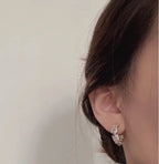 Gold-tone hoop earring with pearl and rhinestone detailing on ear.