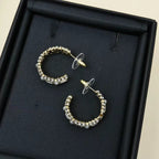 Gold-tone hoop earrings with pearl and rhinestone row, shown in black jewelry box.