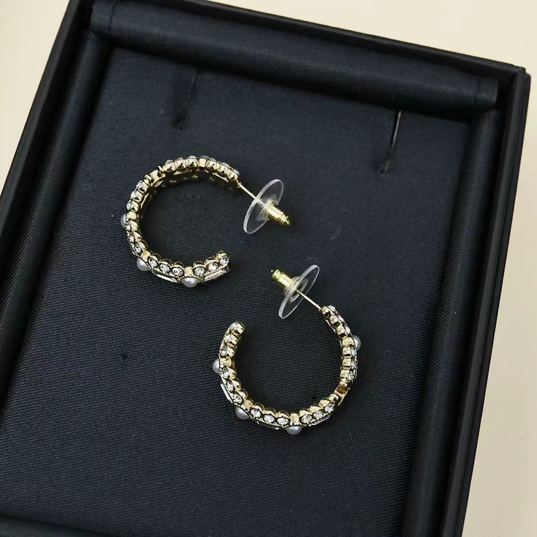 Gold-tone hoop earrings with pearl and rhinestone row, shown in black jewelry box.