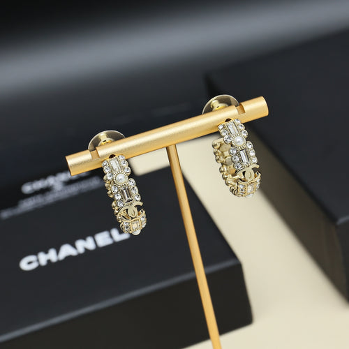 Gold-tone hoop earrings with pearl and rhinestone links on display stand.