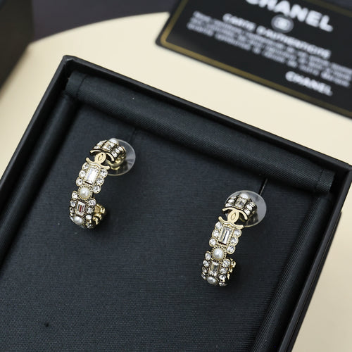 Gold-tone hoop earrings with pearl and rhinestone charms on jewelry box.