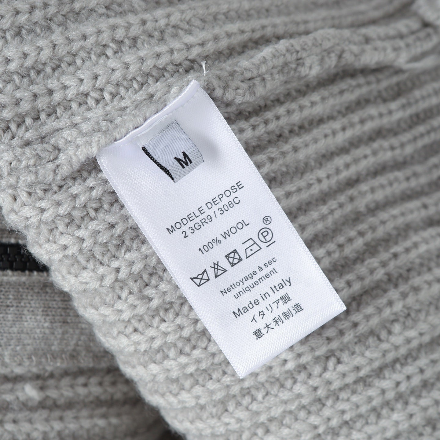 Stone Island knitwear care label on light gray ribbed fabric, size M