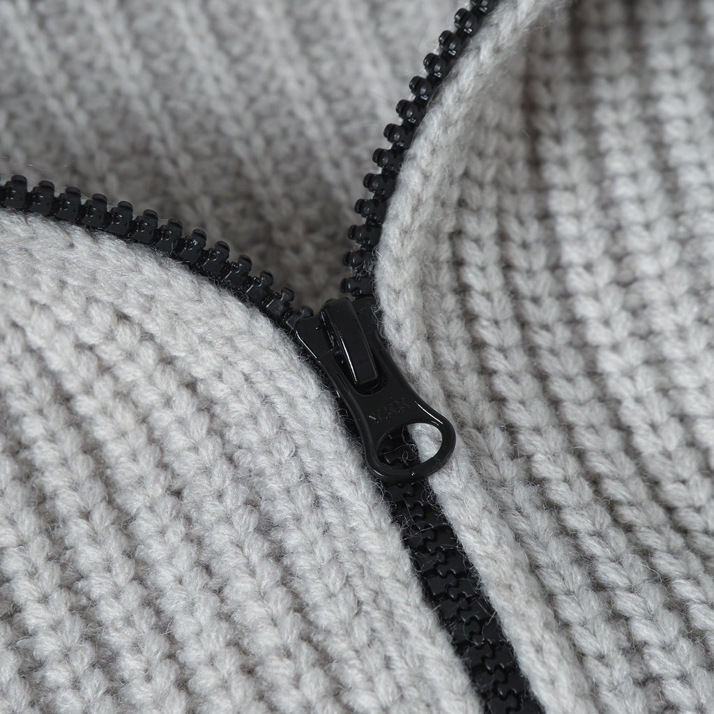 Close-up of light gray knit hoodie with black zipper and pull tab