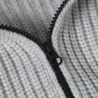 Close-up of light gray knit hoodie with black zipper and pull tab