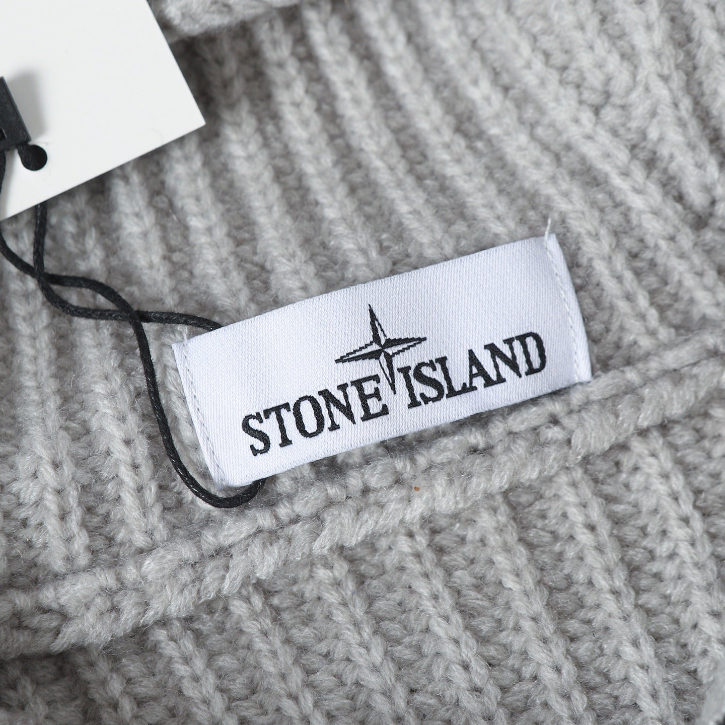 Light gray knit hoodie label at neckline with black zipper pull