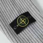 Stone Island knitwear brand patch on light gray knit fabric