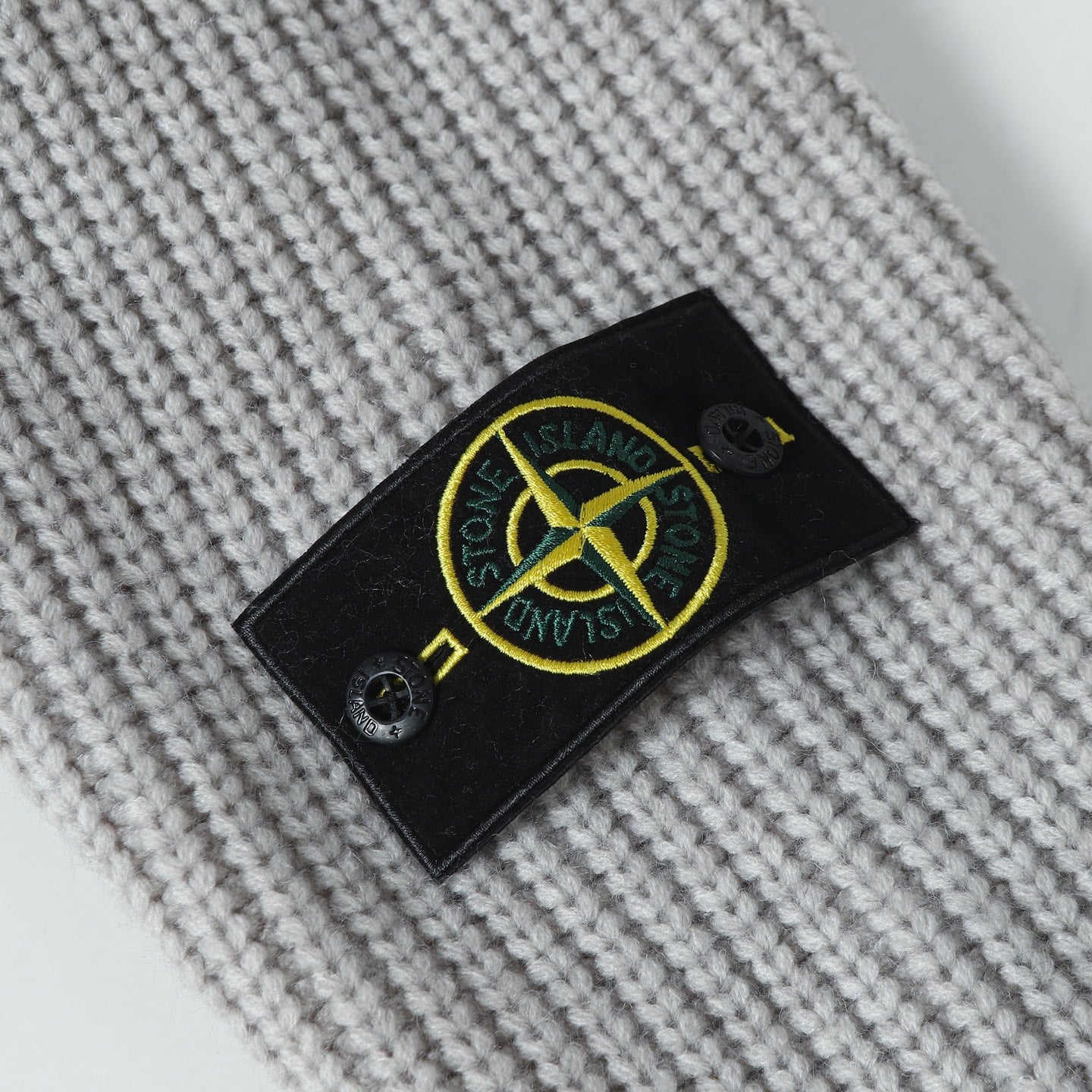 Stone Island knitwear brand patch on light gray knit fabric