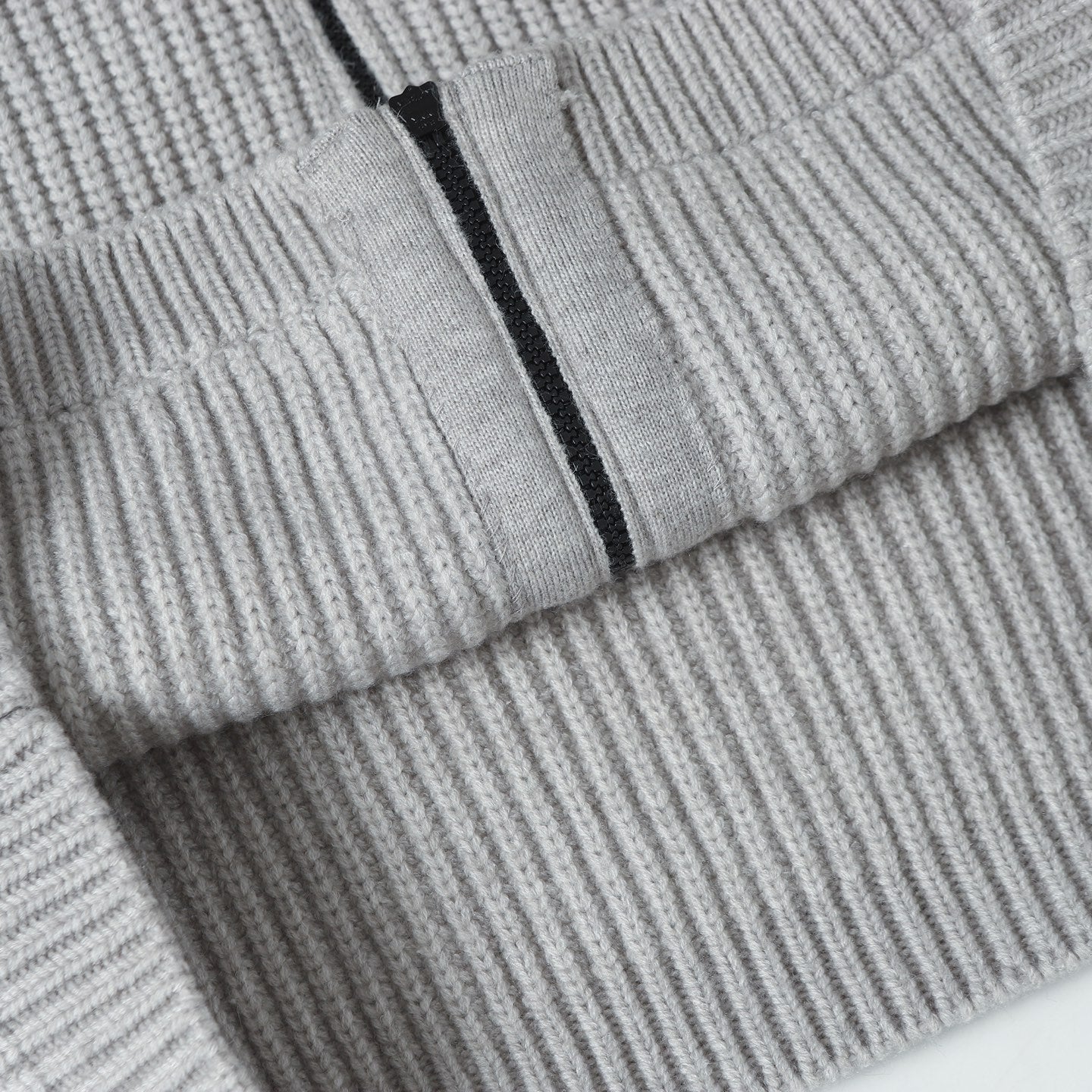 Light gray knit hoodie sleeve cuff with ribbed cuff detail and zipper edge