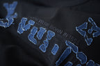 Louis Vuitton black T-shirt close-up with blue embroidered LV-style letters