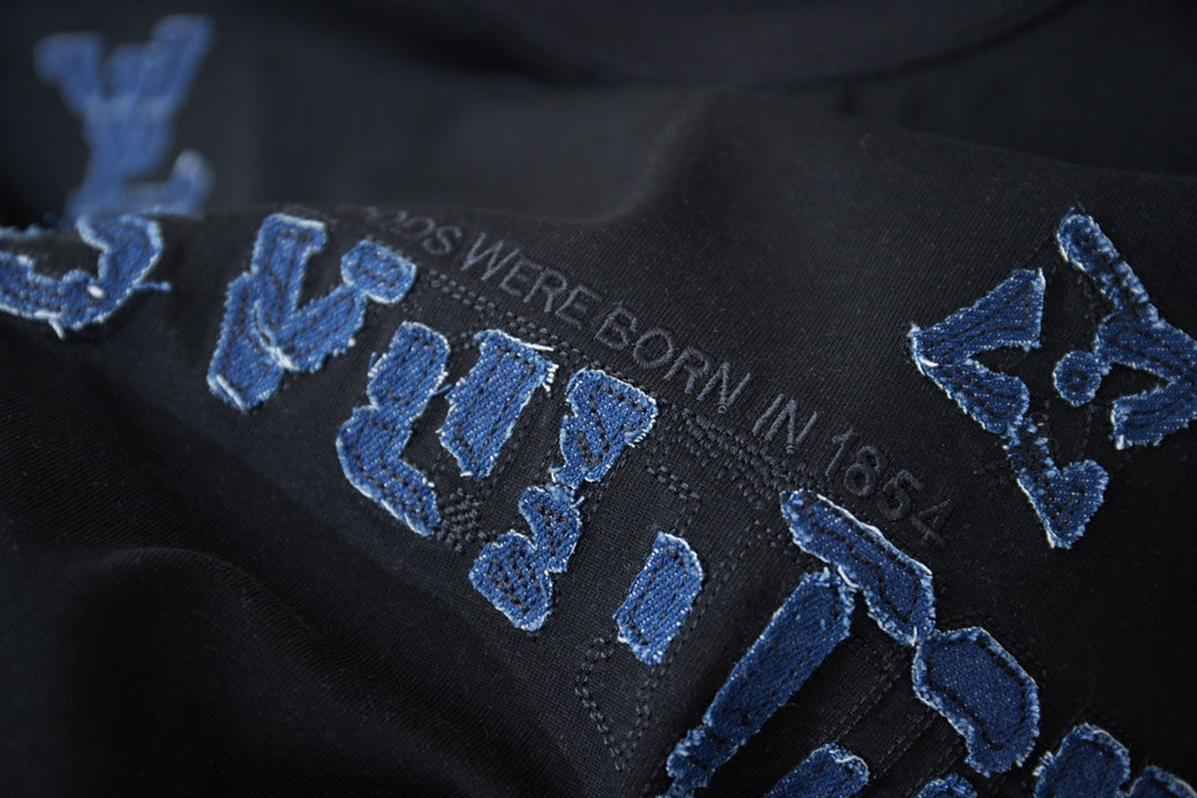 Louis Vuitton black T-shirt close-up with blue embroidered LV-style letters
