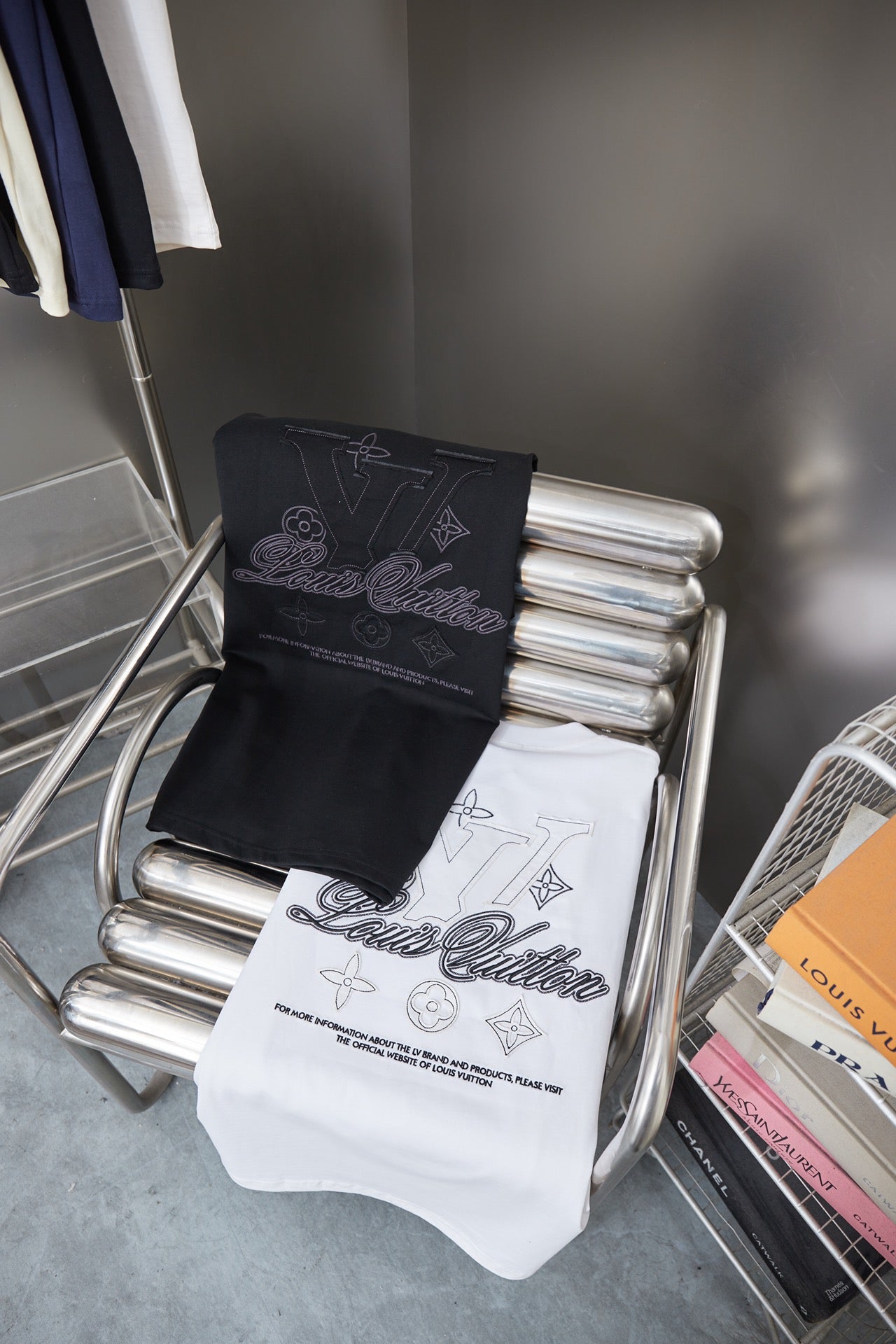 Black and white short-sleeve T-shirts folded on a rack with LV-style script graphics