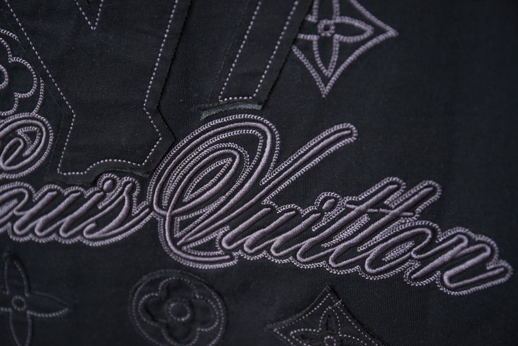 Black short-sleeve T-shirt close-up of embroidered LV-style script and monogram