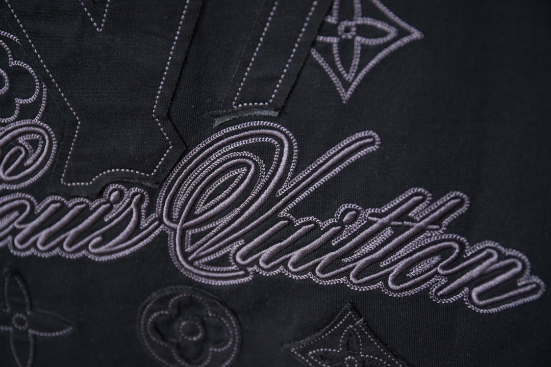 Black short-sleeve T-shirt close-up of embroidered LV-style script and monogram