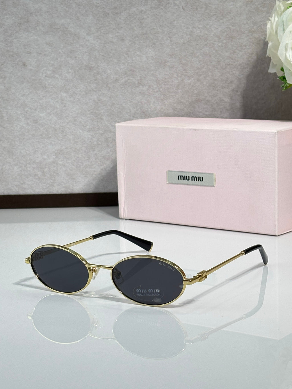 MiuMiu oval eyeglasses with gold-tone metal frame, black temple tips, black lenses
