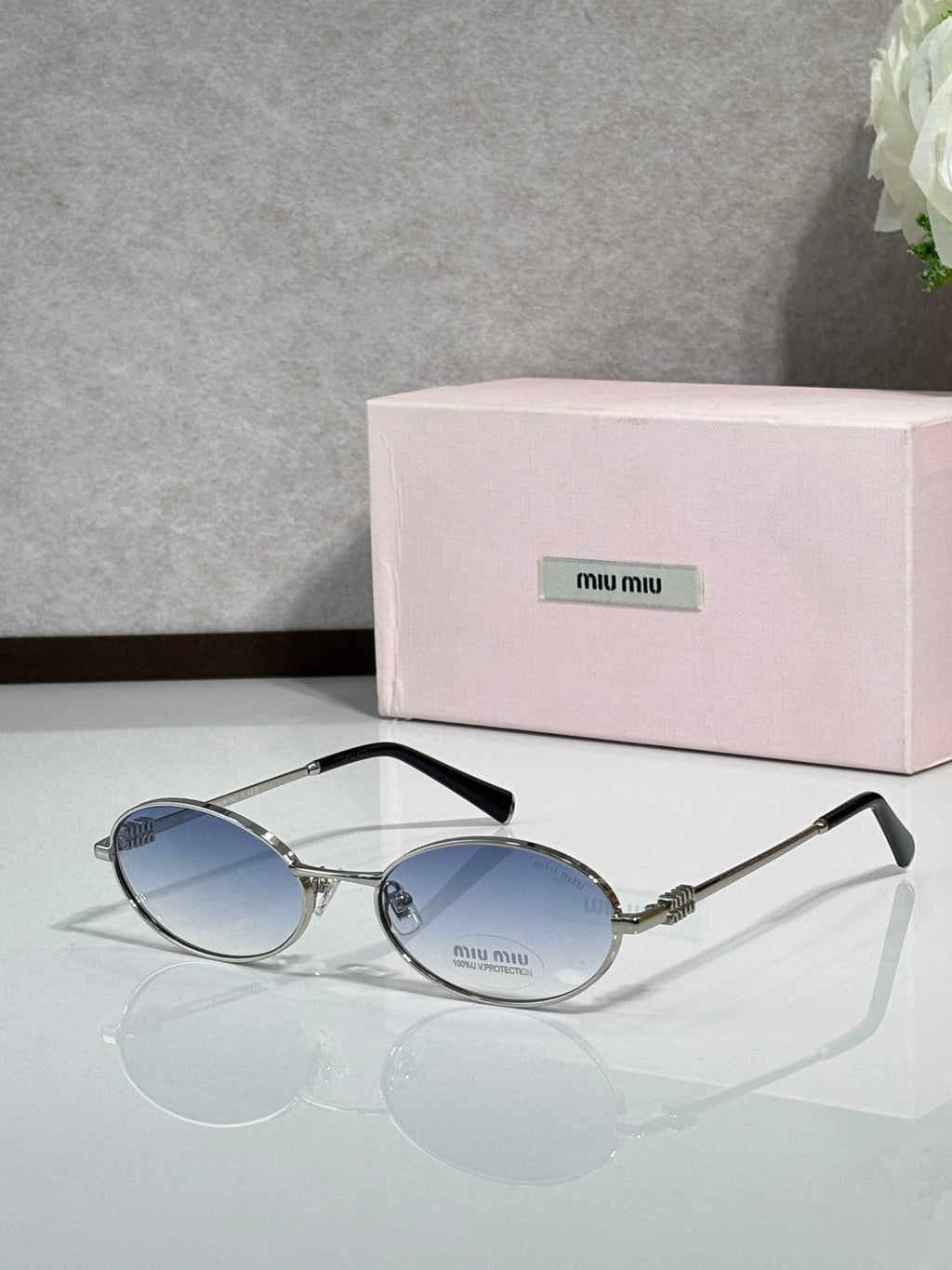MiuMiu oval eyeglasses with gold-tone metal frame and black temple tips, dark blue lenses