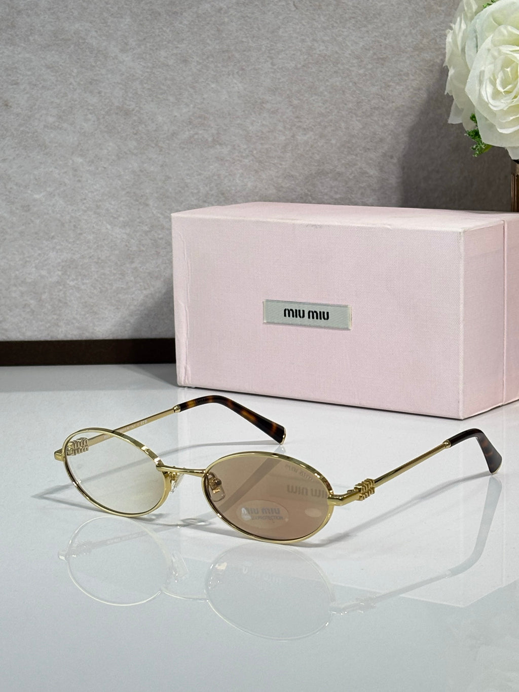 MiuMiu oval eyeglasses with gold-tone metal frame, tortoiseshell bridge, dark lenses