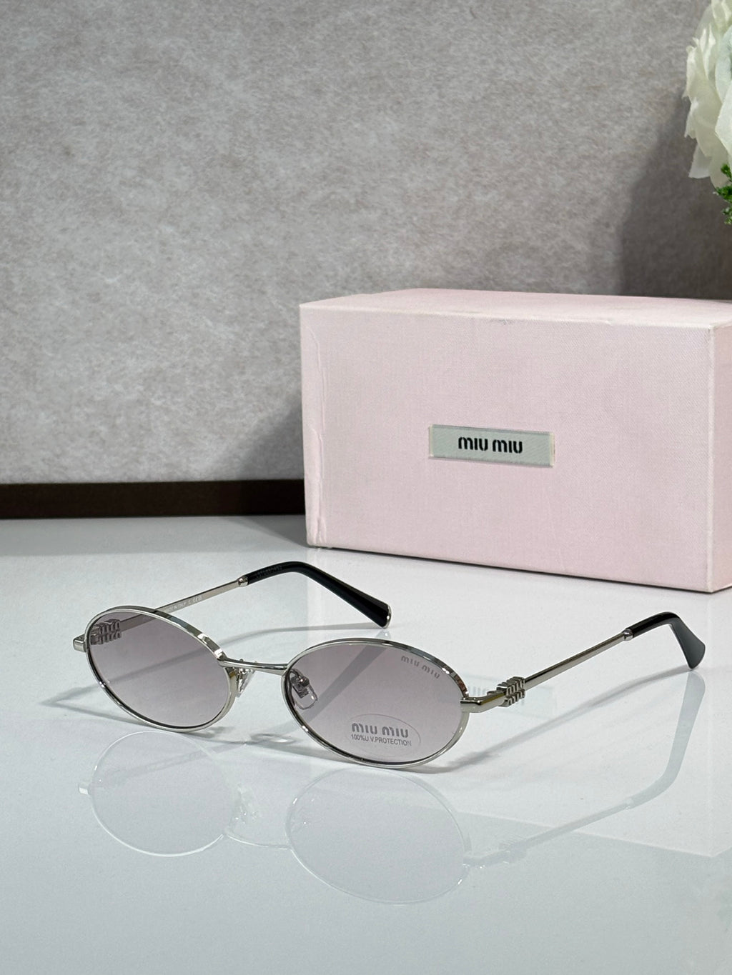 MiuMiu oval eyeglasses with gold-tone metal frame, black temple tips, dark tinted lenses