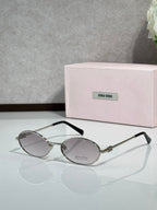 MiuMiu oval eyeglasses with gold-tone metal frame, black temple tips, dark tinted lenses