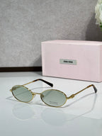 MiuMiu oval eyeglasses with gold-tone metal frame, black temple tips, light green lenses