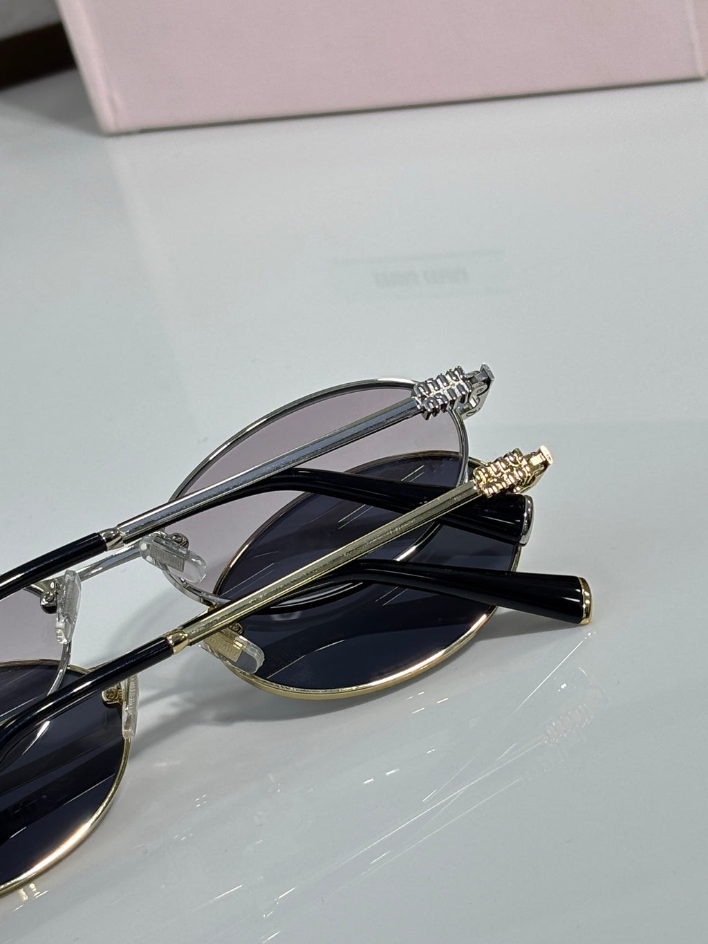 MiuMiu oval eyeglasses close-up with gold-tone hinges and black temple tips