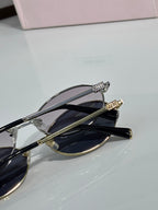 MiuMiu oval eyeglasses close-up with gold-tone hinges and black temple tips