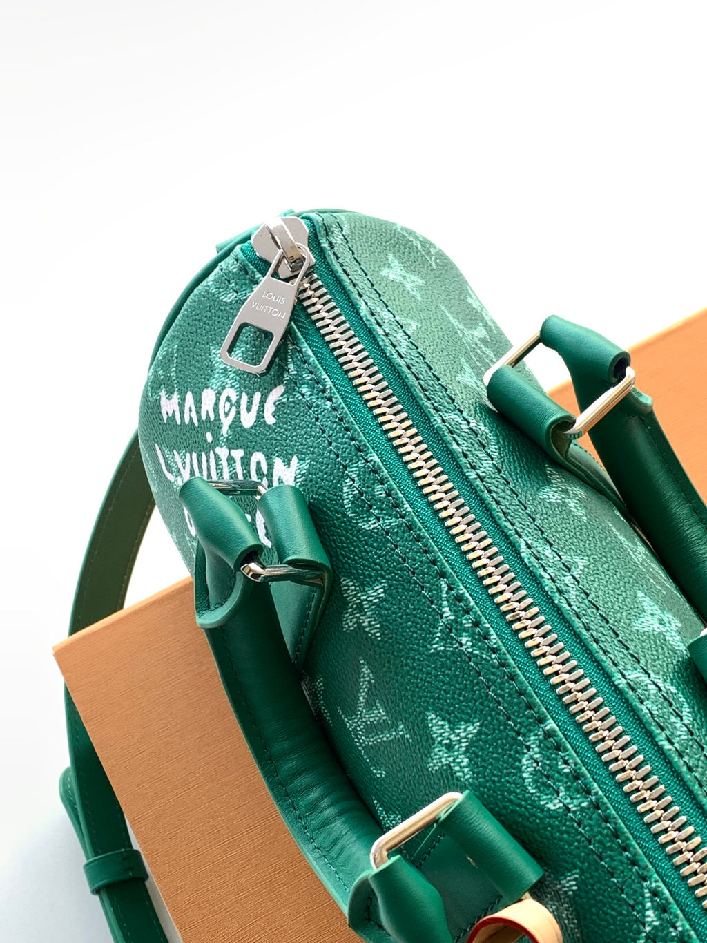 Louis Vuitton green monogram bag showing zip pull and brand patch tag